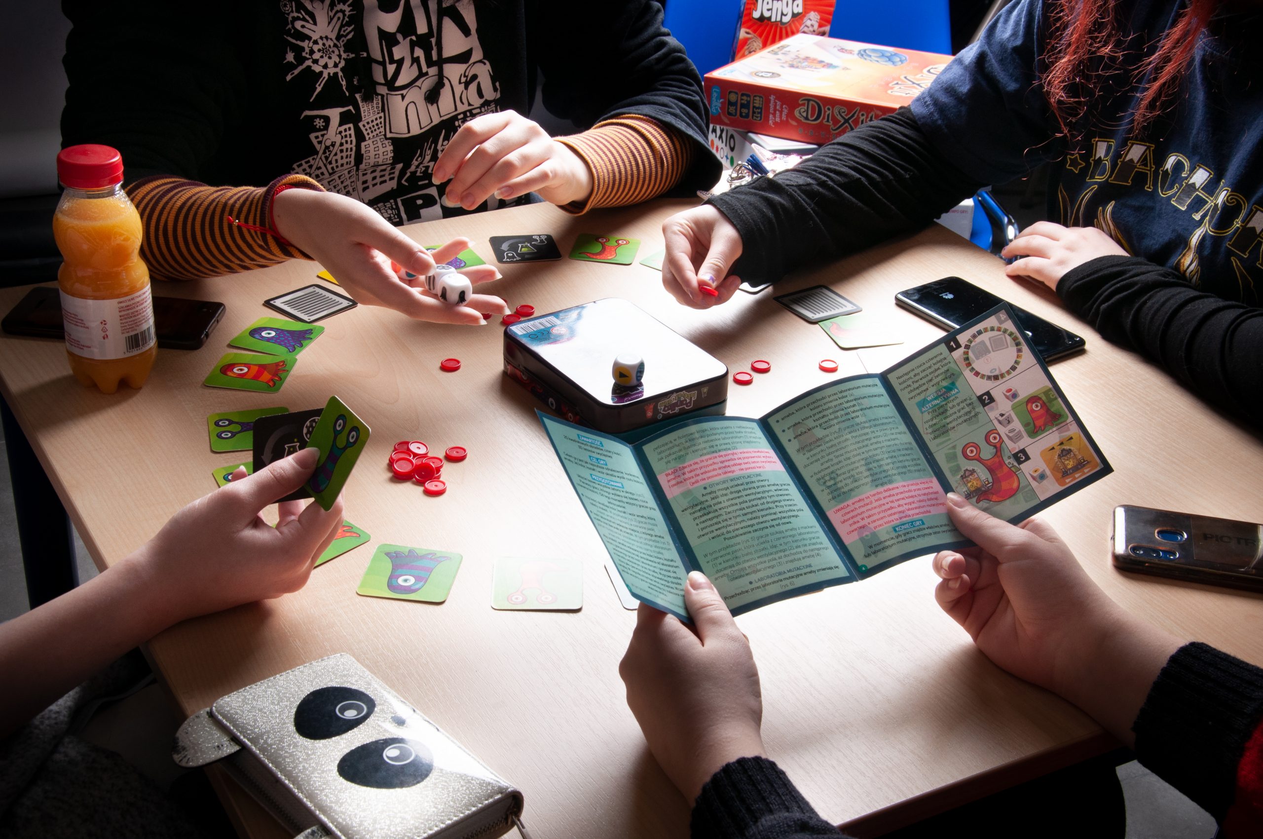 cztery osoby grają w grę planszową, na stoliku karty do gry