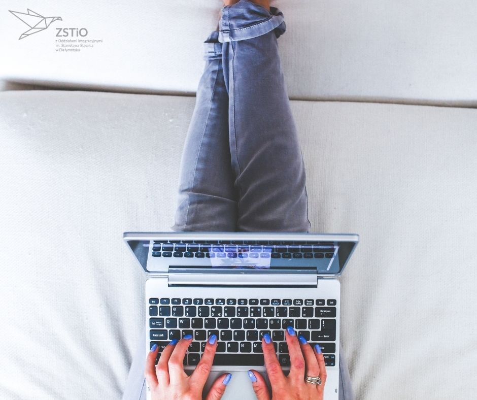 kobieta w jeansach z niebieskimi paznokciami korzysta z laptopa