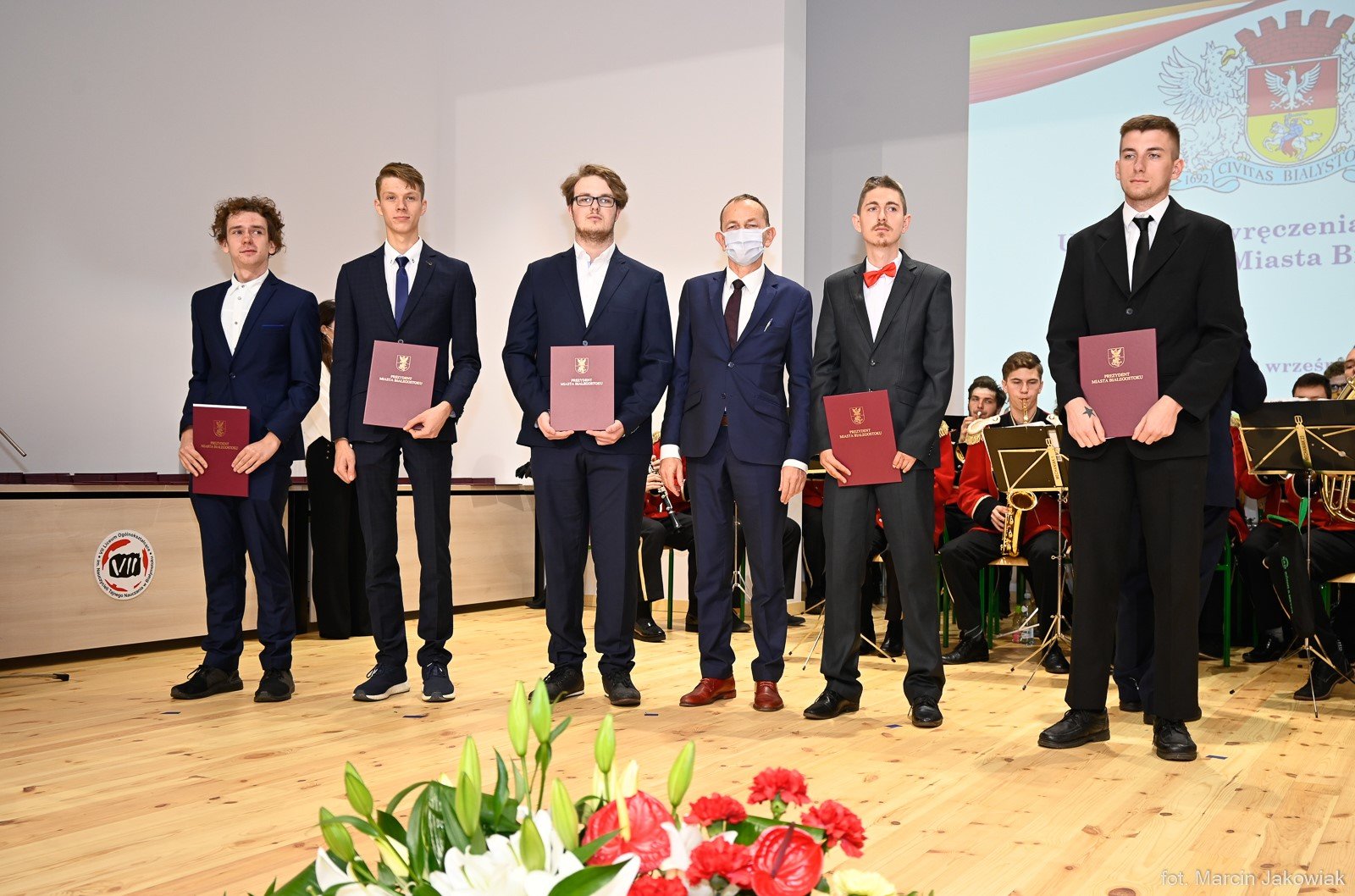 6 mężczyzn, w rękach trzymają bordowe teczki z napisem dyplom i godłem Polski