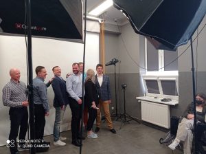 grupa 6 mężczyzn i kobieta stoją w sali fotograficznej, pozują do zdjęcia