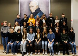grupa kulkunastu młodych osób pozuje do zdjecia, w tle portret Stanisława Staszica