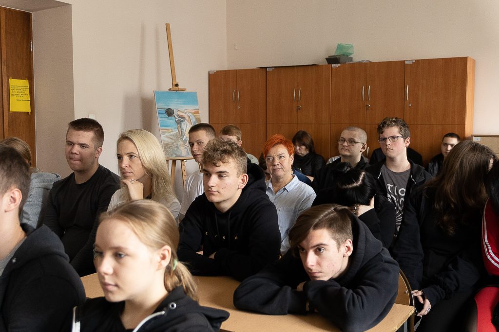grupa uczniów siedzi w klasie przy ławkach szkolnych