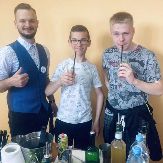 trzech mężczyzn pozuje do zdjęcia, dwóch ma szklanki z napojem ze słomkami