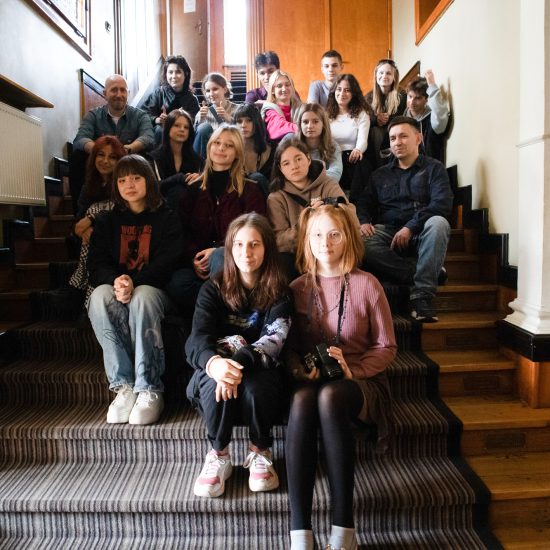 grupa uczniów siedzi na schodach szkoły filmowej