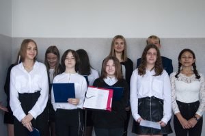 młodzi ludzie, dziewczyny, patrzą się w stronę obiektywu, ubrane w białe bluzki i czarne spodnie.