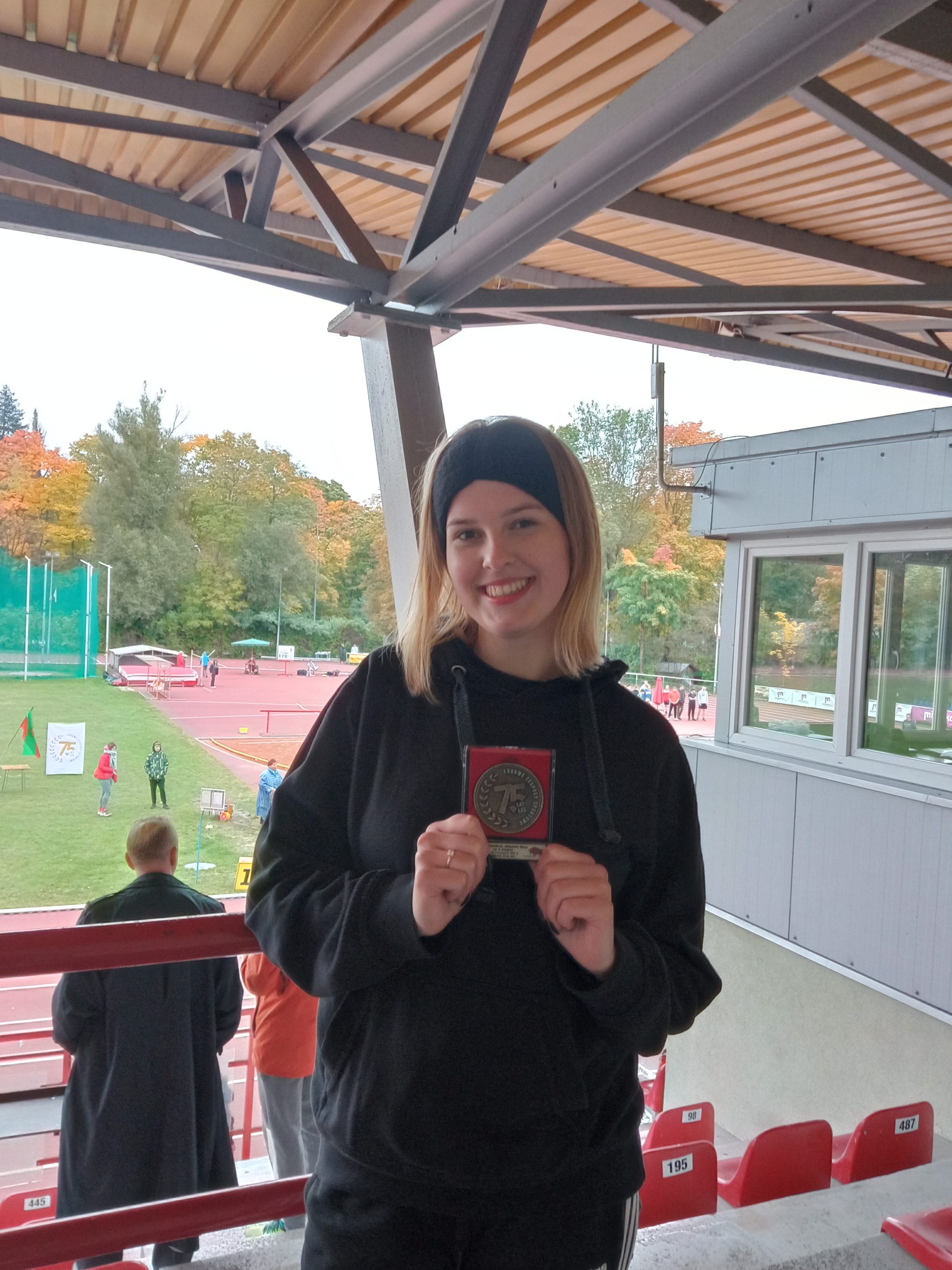 młoda dziewczyna , w ręce trzyma srebrny medal