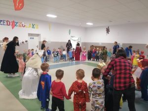 grupa dzieci i dorosłych tańczy w kole, trzymają sie za ręce