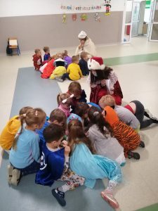 grupa dzieci siedzi na podłodze i czyta książki