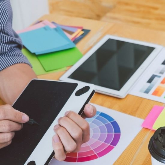 męskie dłonie, w dłoniach tablet, na stole próbniki kolorystyczne