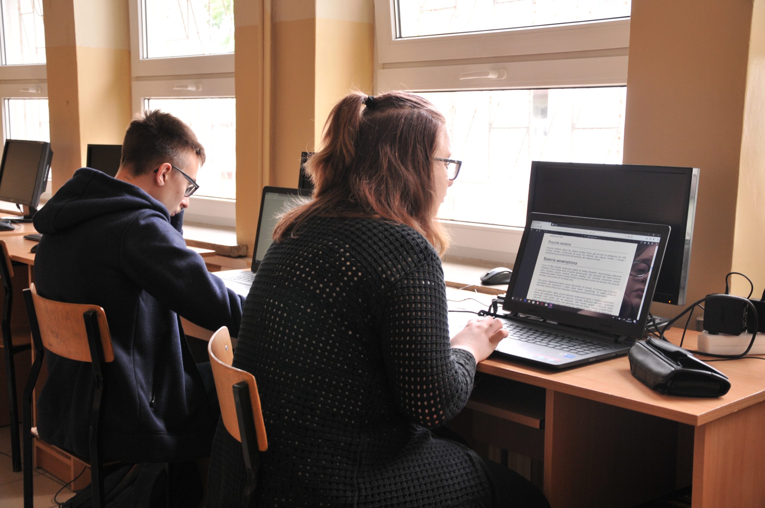 uczniowie pracujący na laptopach