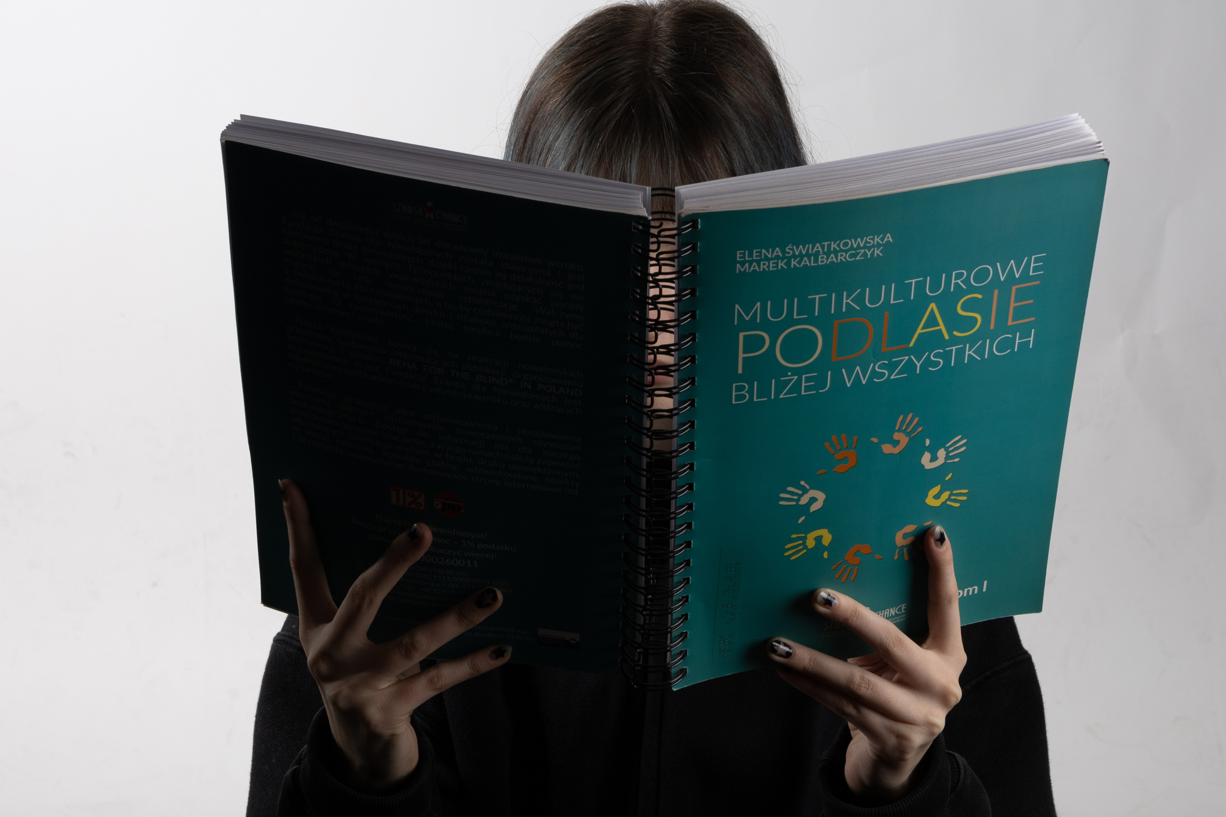 postać trzyma książkę okładką do oglądającego zdjęcie