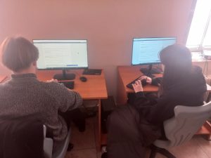 grupa uczniów siedzi przy stoiskach komputerowych w sali lekcyjnej