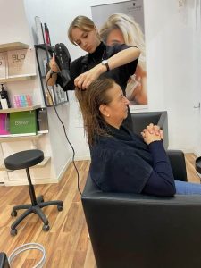 młoda dziewczyna w salonie fryzjerskim suszy włosyobiecie