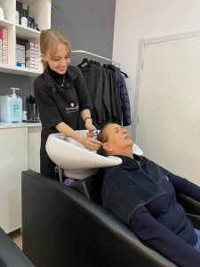 młoda dziewczyna w salonie fryzjerskim myje włosy kobiecie