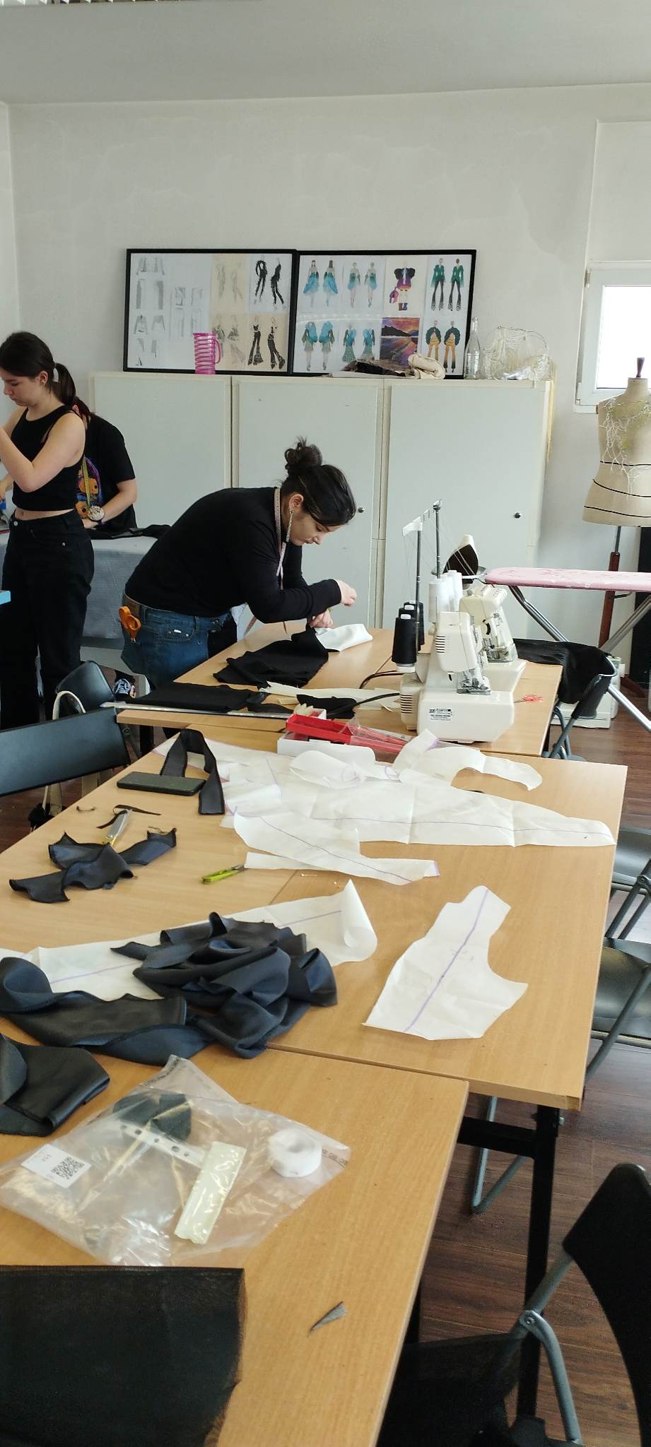 młoda dziewczyna przy stole szyje ubranie