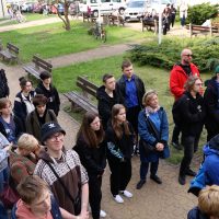 grupa uczniów i nauczycieli stoi na podwórku na placu szkoły