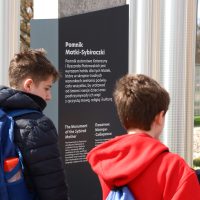 2 uczniów stoi obok pomnika